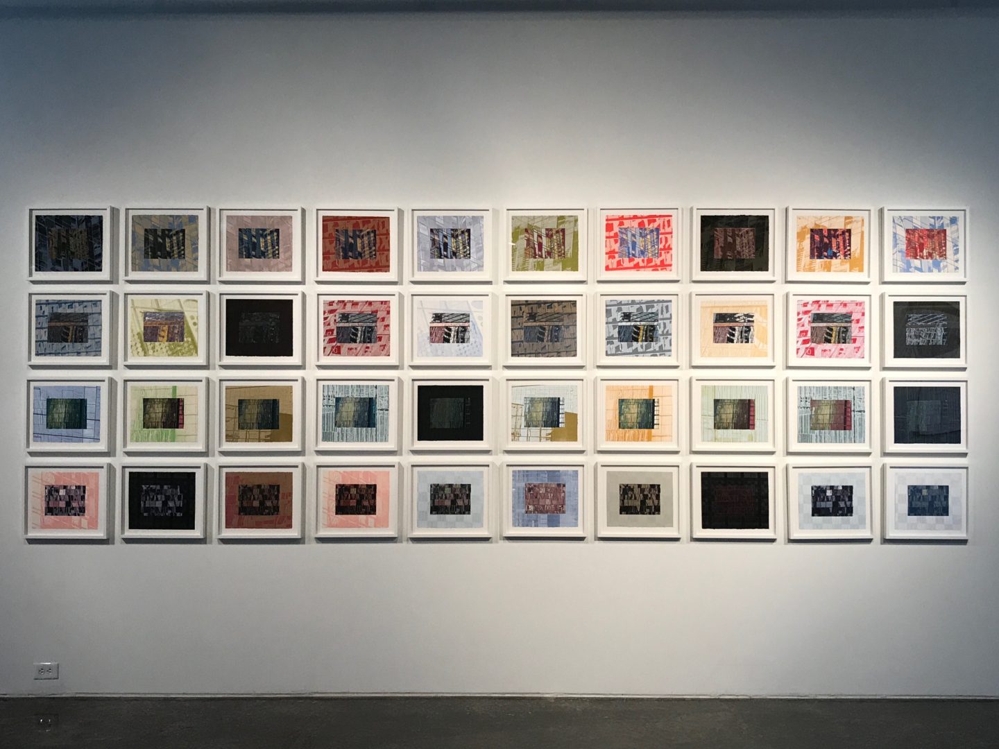 A wall with many frames of different colors and sizes.